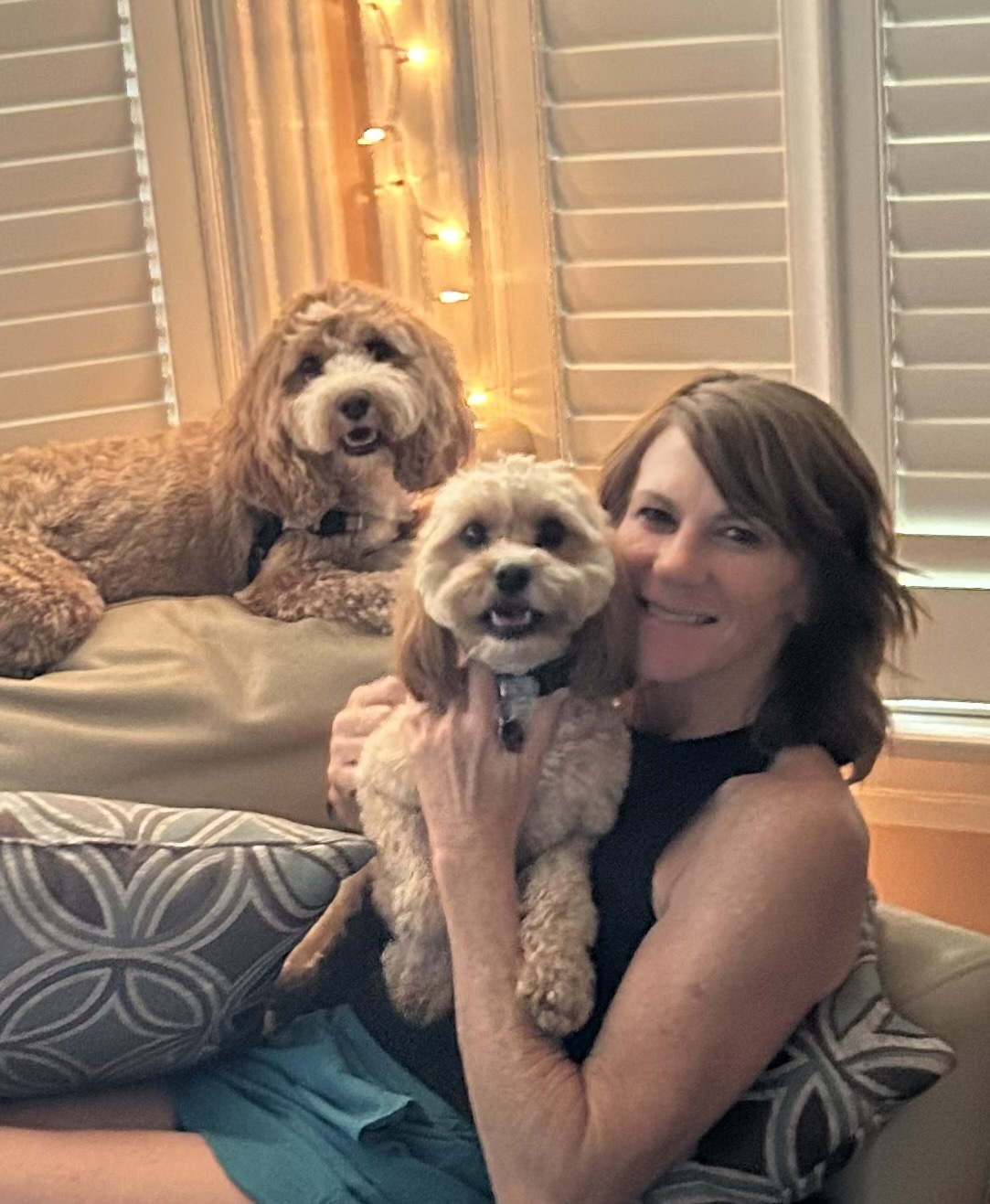 Lauren cuddling two dogs in her home